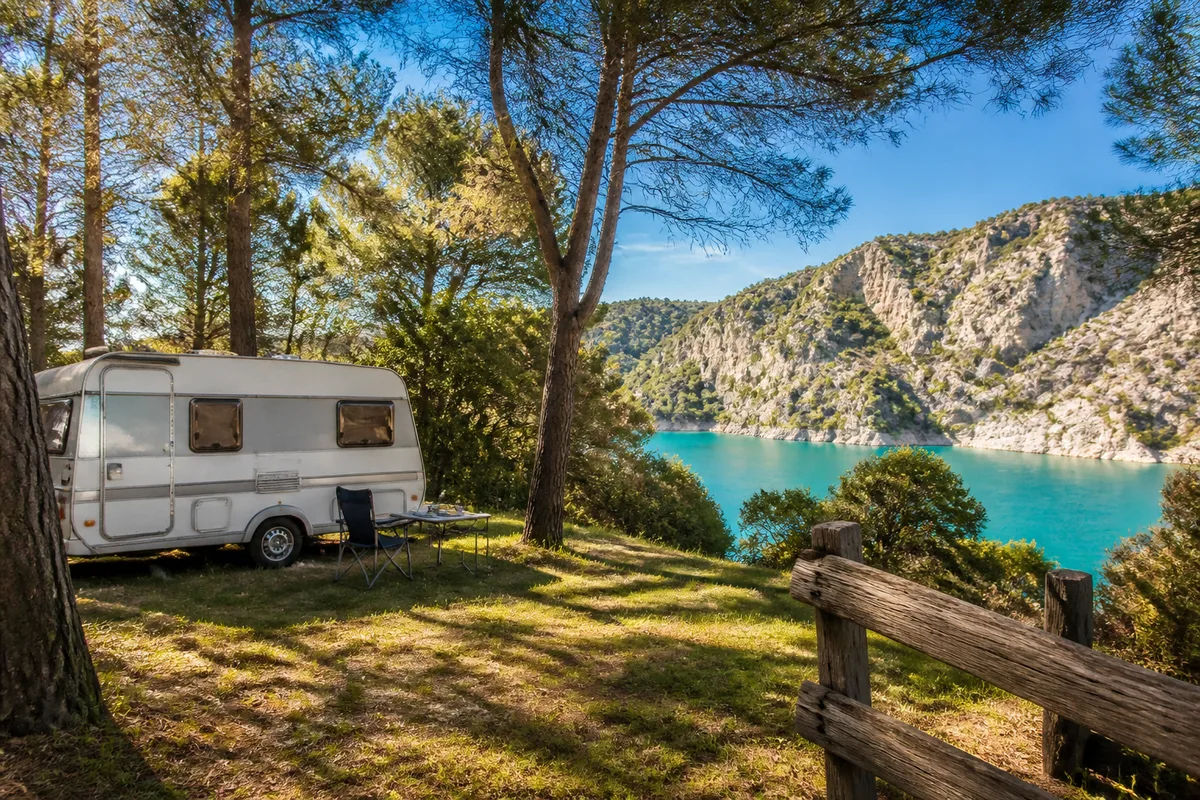 Caravane installée sur un emplacement herbeux entouré de pins en Provence